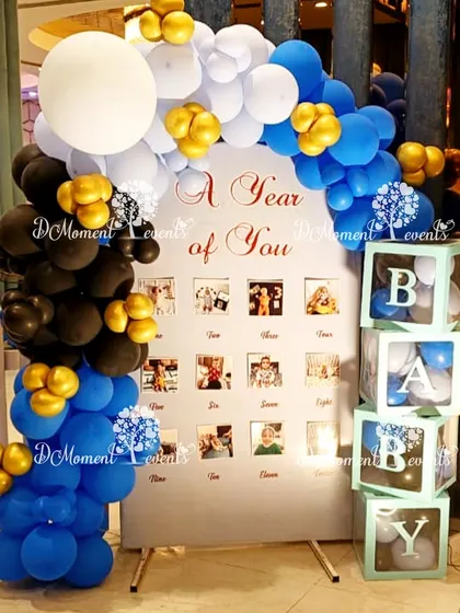 A "Year of You" milestone board for a Boss Baby theme, framed with a stylish black, blue, and gold balloon arch.