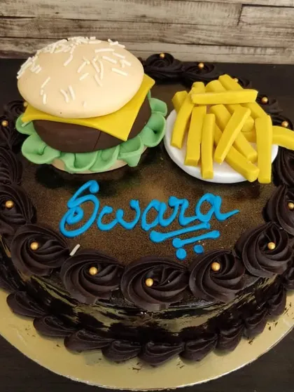 A cake for the ultimate fast-food lover. This design features a rich chocolate cake topped with a fully edible, sculpted burger and fries made from fondant.