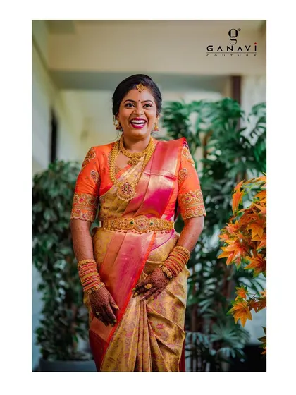 A full, happy smile from bride Yamuna. Her orange embroidered blouse adds a pop of color and exquisite craftsmanship to her traditional silk saree.