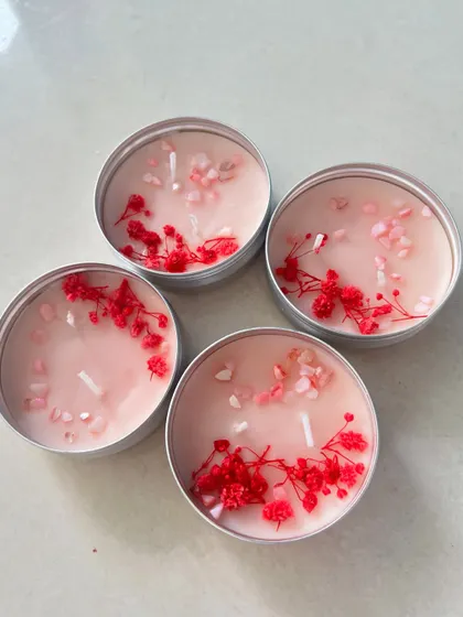 A set of four travel tin candles with dried red flowers and crystals.