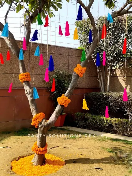 Even the trees become part of the decor. Here, I adorned a tree with colorful tassels and marigold garlands, turning a simple garden element into a vibrant part of the Haldi celebration.