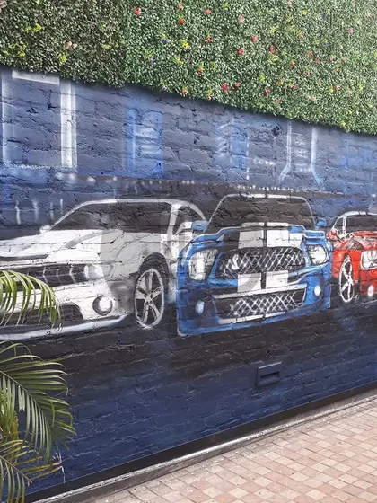A realistic mural of classic muscle cars for Walking Street, Gurgaon. This piece captures the power and beauty of these iconic vehicles, perfect for an automotive enthusiast or a themed venue.