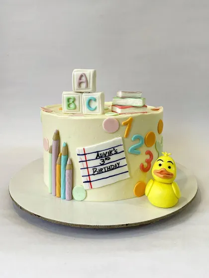 An adorable school-themed cake for a third birthday. This design celebrates learning with fondant ABC blocks, colored pencils, and a cute rubber ducky.