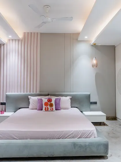 This bedroom is all about feminine charm. A fluted pink wall panel serves as a stunning backdrop for the bed, while the circular mirror and vanity add a touch of elegance.