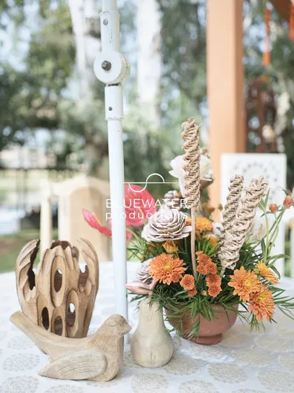 A tabletop centerpiece with wooden bird figurines and a mix of dried and fresh flowers.
