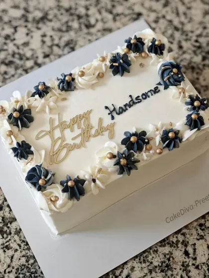 A handsome rectangular coffee cake with buttercream frosting. The design is masculine yet elegant, with piped navy blue and white flowers and gold accents.