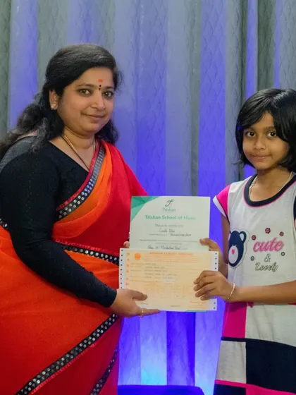 A young achiever with her music exam certificate. My structured curriculum is designed to help students excel in exams from boards like ABRSM and Trinity.