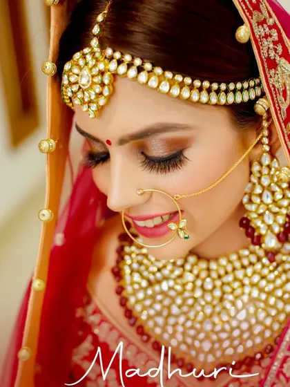 A breathtaking close-up of the bride Madhuri. This portrait focuses on her flawless makeup, traditional jewelry like the nath and maang tikka, and her serene expression.