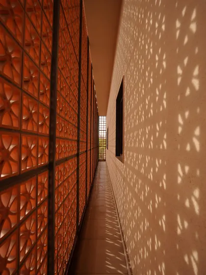 A key feature of The Lantern House is the perforated terracotta jaali that caps the home. It acts as a climate tool by blocking harsh sun, serves as a privacy screen, and transforms the house into a glowing lantern at night.