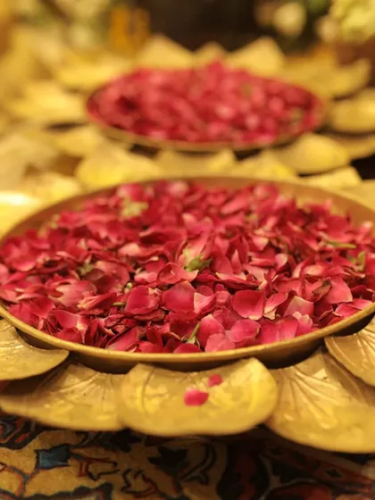 A decorative brass plate filled with fresh rose petals, ready for the Haldi rituals and adding a touch of traditional elegance.