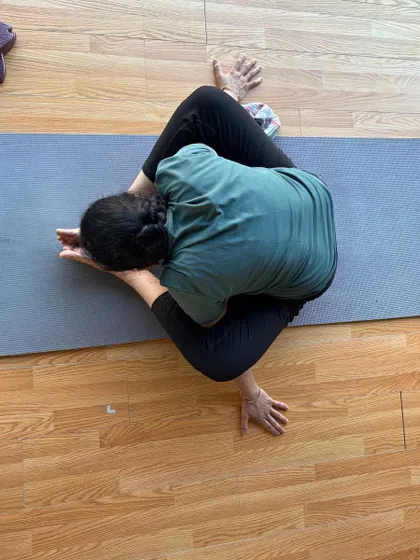 An overhead view of a student in a deep twisting pose, showcasing spinal mobility.