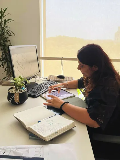 A designer sketching on a tablet, with notebooks and plans nearby. This showcases the modern tools and creative process that drive our daily work at the studio.