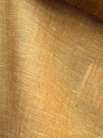 A close-up of a beautiful mustard-colored linen fabric. Linen offers a unique texture and is exceptionally breathable for summer wear.