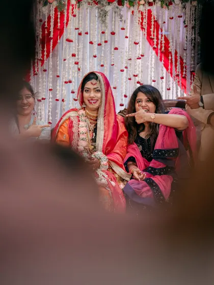 A fun, candid moment between the bride and a friend or family member. This photo, shot through a gap, feels like a secret, joyful memory captured forever.