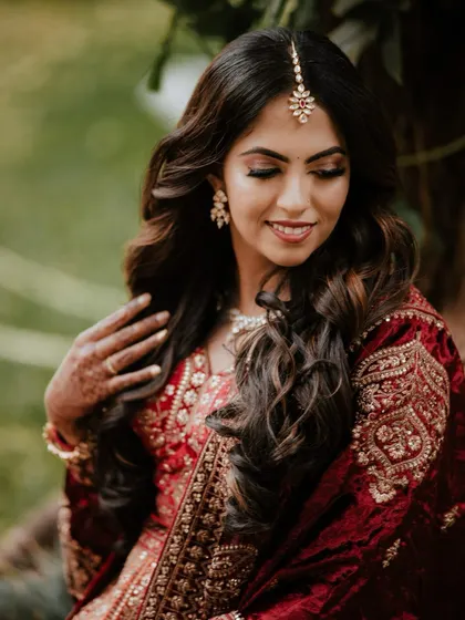 An elegant portrait of the bride, showcasing her beautiful hair, makeup, and reception lehenga.