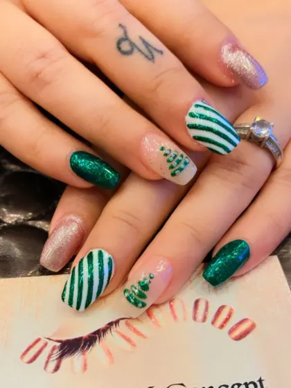 A festive Christmas-themed nail art set. It includes green glitter nails, striped candy cane patterns, and accent nails with hand-painted Christmas trees.