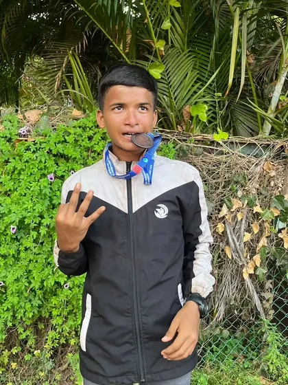 Piyush biting his bronze medal, a classic champion's pose after a hard-fought race.