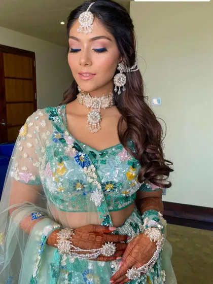 The bride looks ethereal in her pastel green lehenga, with her hair styled in soft, romantic waves.