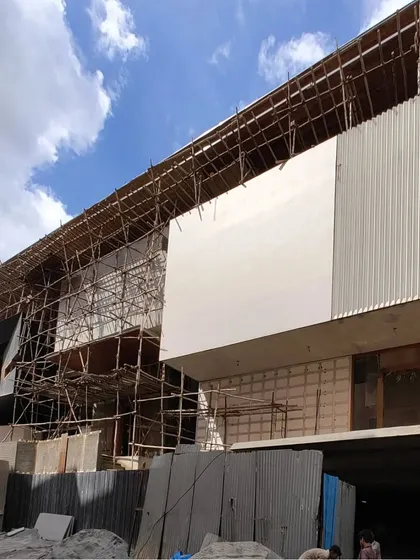 The large-scale facade of the 'House of Reddys' being clad, showing the combination of different materials and textures.