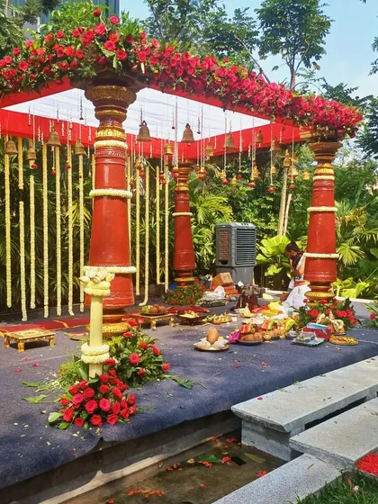 A full view of the traditional red-pillared mandap, set up for an outdoor wedding.