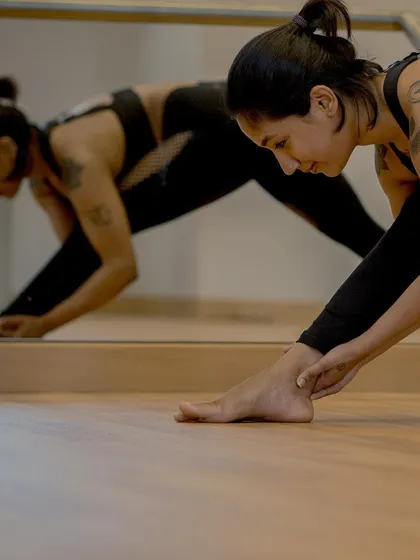 Finding length in the hamstrings and spine with Parsvottanasana, or Pyramid Pose. The mirror helps us observe our alignment, ensuring we are moving with intention and protecting our bodies as we stretch.