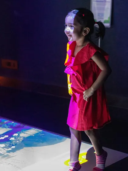 A young guest enjoying the interactive floor at Project Play, a space designed to spark imagination.