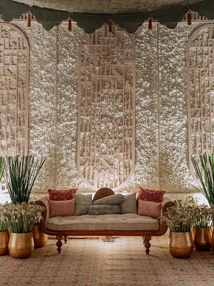 For this event, we created a serene backdrop using panels with intricate, hand-carved textures. The space is decorated with traditional Indian seating and brass pots filled with tuberoses.