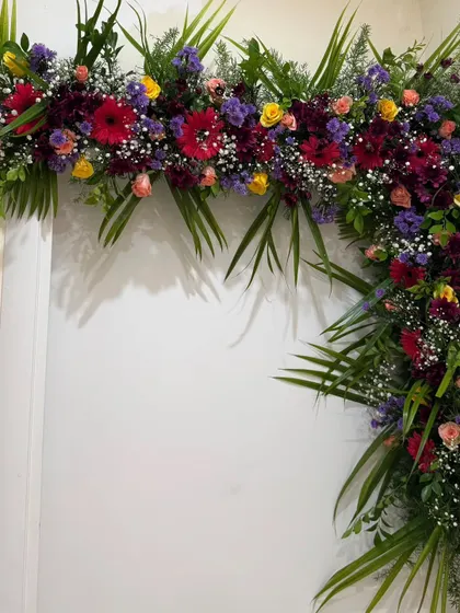 In this design, I used prominent palm leaves to give the floral arch a more tropical and lush feel. The bright red gerbera daisies provide a striking pop of color against the deep green foliage.