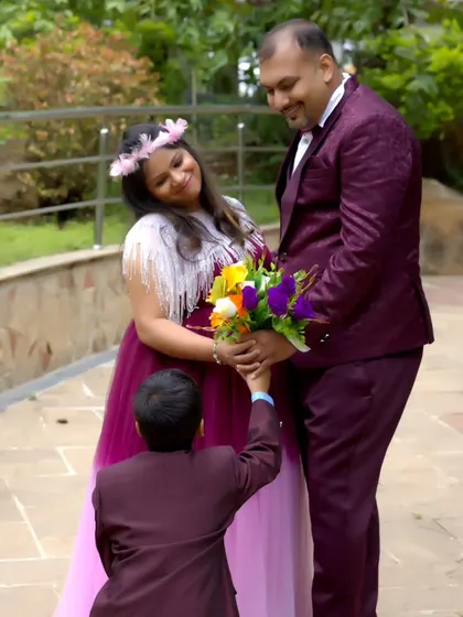 A sweet family moment, with the older brother offering a bouquet of flowers to his parents during their maternity shoot.