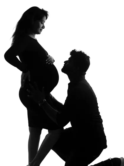 A classic silhouette of the father-to-be gazing up at the baby bump, a simple and powerful image of love.