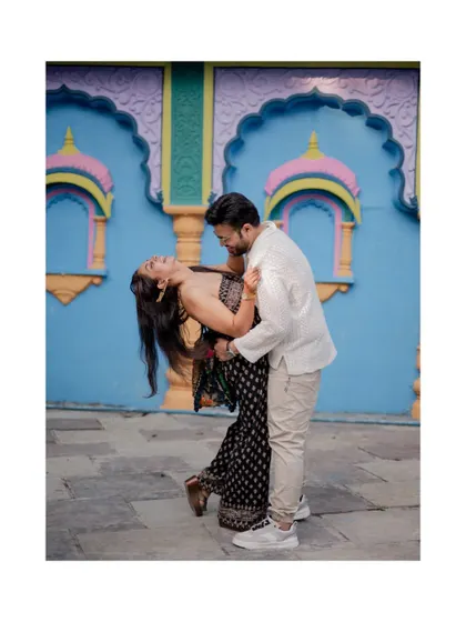 A classic romantic dip pose against a colorful, traditional Indian wall, adding a vibrant and cultural element to their pre-wedding photos.