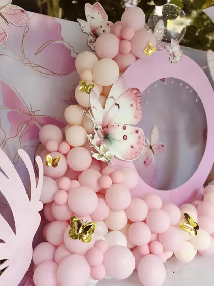 Another view of the pastel pink butterfly decor, focusing on the round photo-frame panel and the mix of small and large butterfly accents.