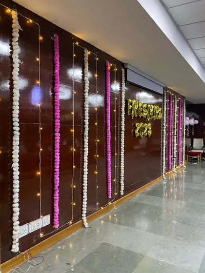 Wall decorations for a fresher's party, using fairy lights and traditional flower garlands.
