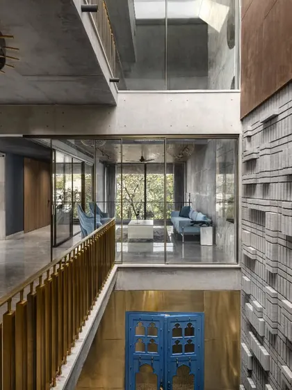 The Swatantra Residence is designed as an inward-looking home with a triple-height courtyard at its core. This view from the upper bridge shows the visual link between all spaces, with light filtering down through the multi-level cut-outs.