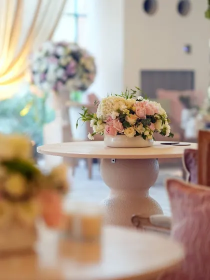 A detail shot of a floral arrangement on a side table, showing the soft focus and romantic atmosphere we create. The mix of pink and white roses is timeless and elegant.