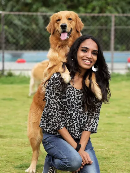 This Golden Retriever knows how to photobomb perfectly, resting his paws on his mom's shoulders for a cute picture.