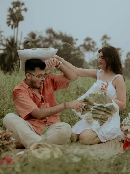 A playful pillow fight in the middle of their picnic, capturing their fun-loving personalities.