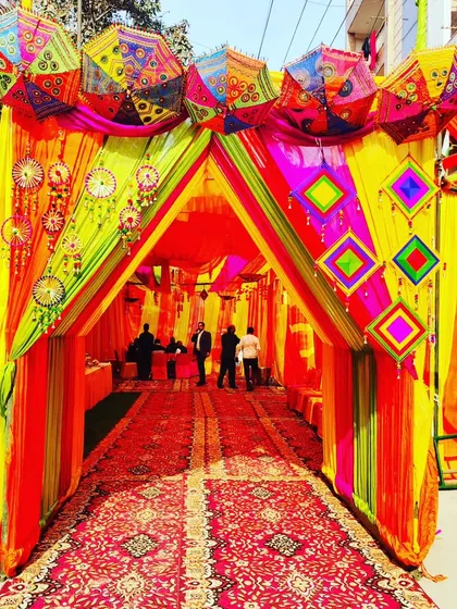 No space is too challenging. Here, I've converted an outdoor area into a grand, festive venue with a colourful tent entrance, perfect for a Haldi or Mehendi ceremony. The setup includes traditional Rajasthani umbrellas and intricate drapery.