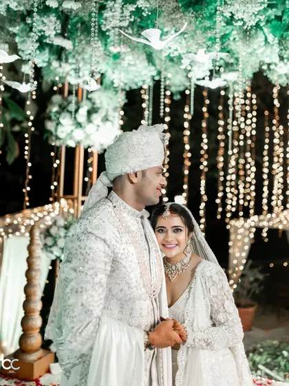 A quiet moment for the newlyweds. The bride rests her head on the groom's shoulder, both looking serene against a backdrop of fairy lights.