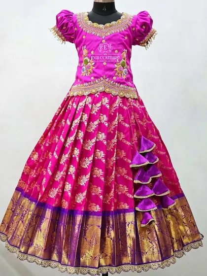 A magnificent pink and purple lehenga with a unique side ruffle detail on the skirt. The pink Banarasi skirt is paired with a heavily embroidered blouse for a truly festive look.