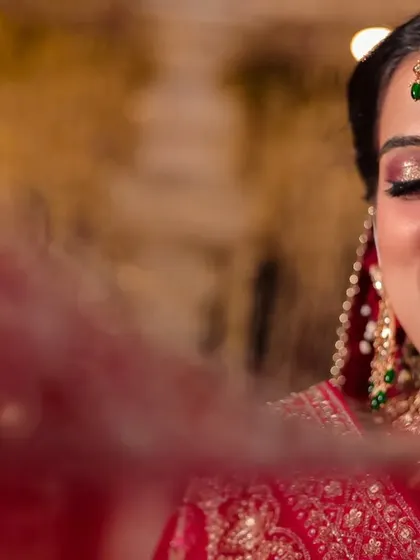 A joyful, smiling portrait of the bride, her face partially veiled, capturing a moment of pure happiness.