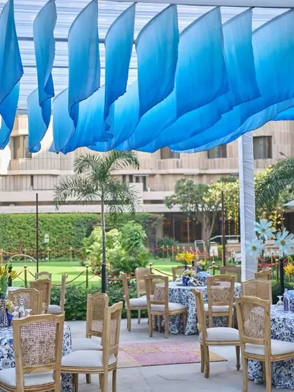 A wide view of the open garden dining area, with a canopy of flowing blue drapes creating a beautiful wave-like effect overhead.