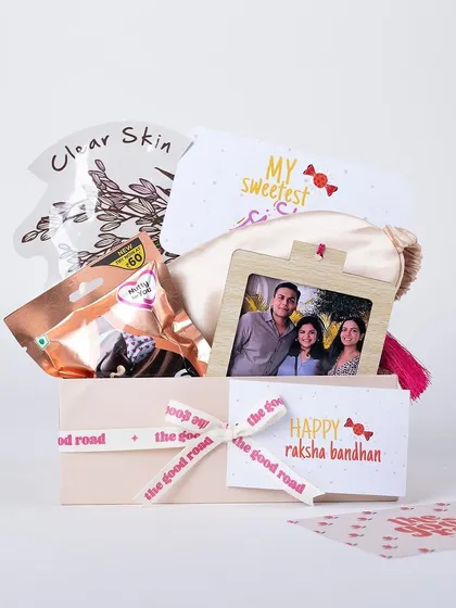 A sweet and simple Rakhi gift hamper for a sister, including a face mask, a personalized photo frame, and her favorite treats.
