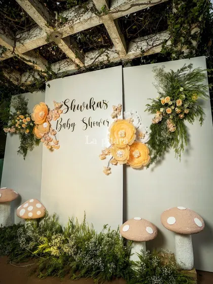 A custom photo backdrop for the baby shower, featuring large paper flowers and whimsical mushroom props. This provided a perfect spot for guests to capture memories of the special day.
