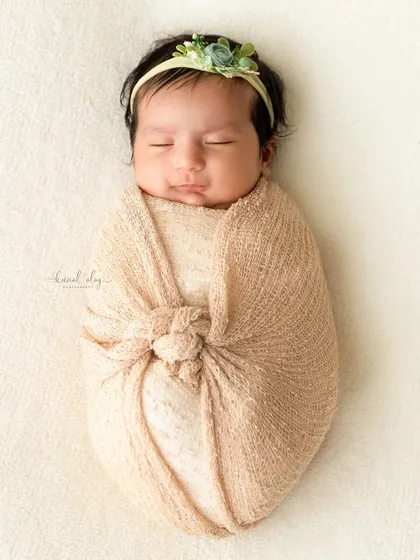A newborn is snugly wrapped in a beige swaddle, showcasing a safe and comfortable wrapping technique that keeps babies calm.