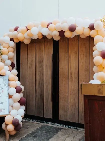 A simple and elegant entrance for a baby shower. A welcome sign is paired with a balloon arch in muted, earthy tones.