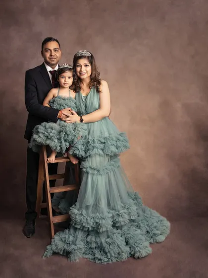 An elegant family portrait. The parents and their daughter, dressed in matching gowns and a suit, look like royalty.