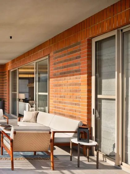The spacious deck of the Max128 apartment, furnished for comfort and relaxation. The use of natural materials like brick and wood connects the space to the earth, creating a perfect urban escape.