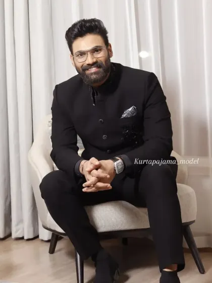 A client looking sharp and confident in a custom all-black Jodhpuri suit. The simplicity of the design is elevated by the perfect fit and a patterned pocket square.