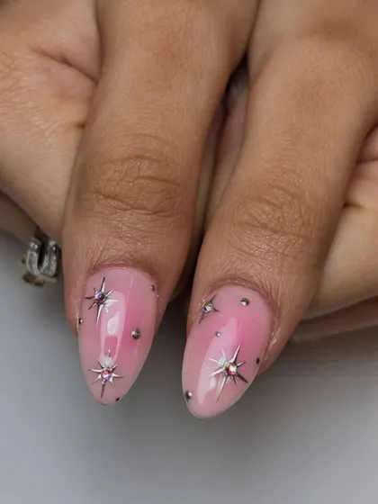 A close-up on the star-studded nails. The tiny gems are carefully placed to create a beautiful constellation effect on the pink ombre base.